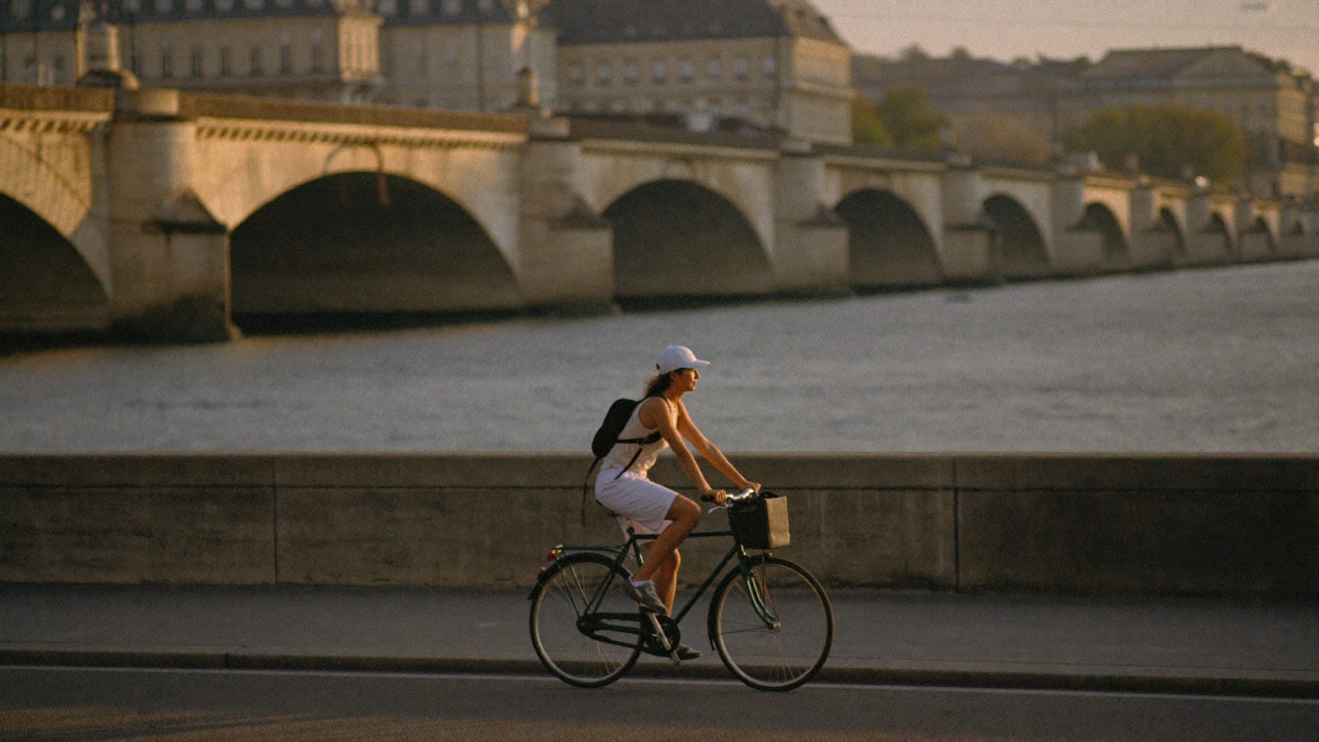 Radfahrerin auf einer Uferstraße vor einer Brücke