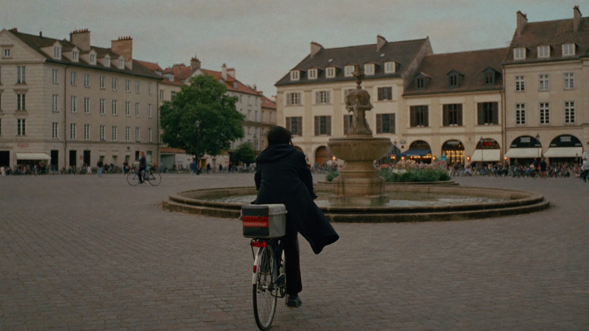 Radfahrerin auf einem Stadtplatz mit Brunnen